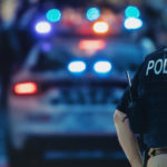 Police officer in vest and patrol car