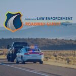 A police vehicle with activated lights stops a truck on a rural road at sunset, with mountains in the background and the 'National Law Enforcement Roadway Safety Program' logo displayed in the corner.