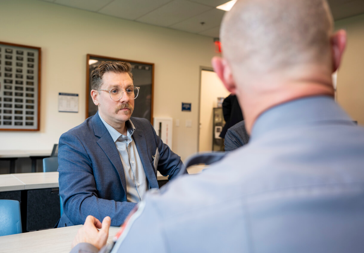 Consultant Meeting with Officer to Discuss Data Quality A consultant listens attentively during a meeting with a uniformed officer in a classroom setting.