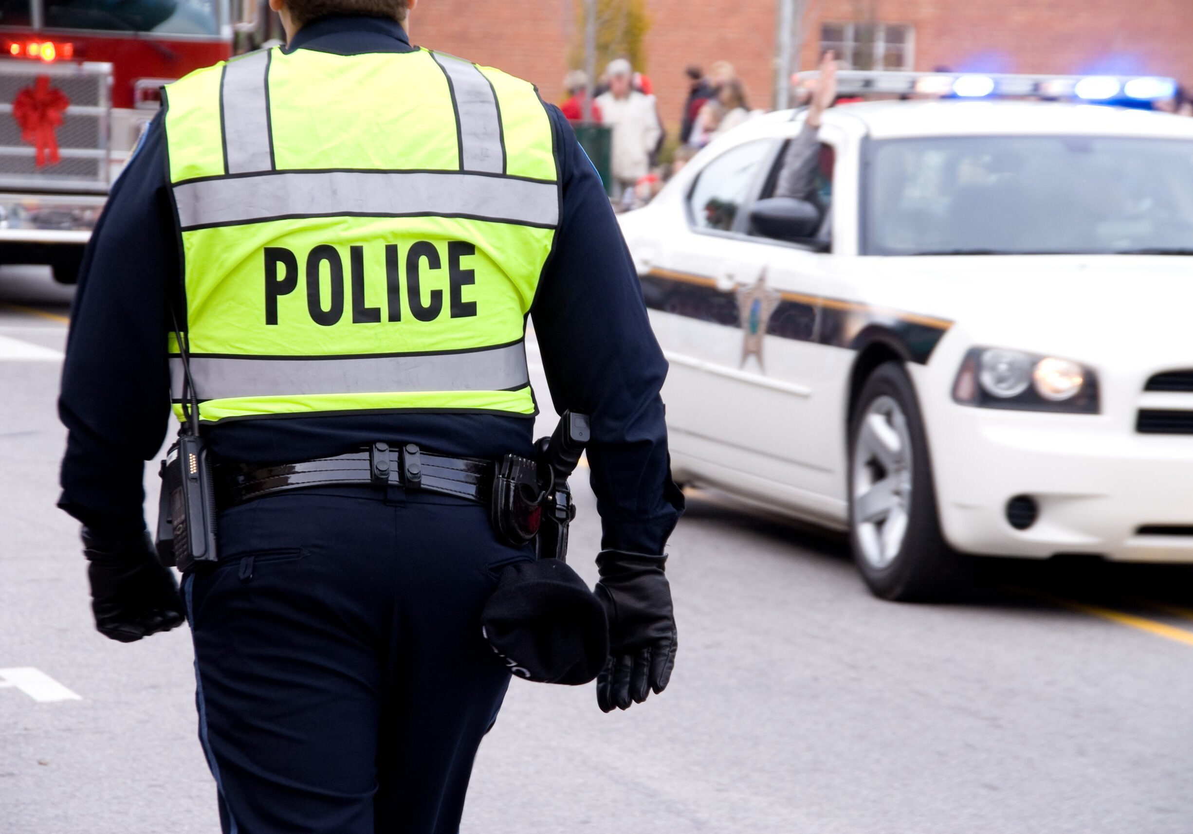 AQ policeman walking by a patrol car on the street.